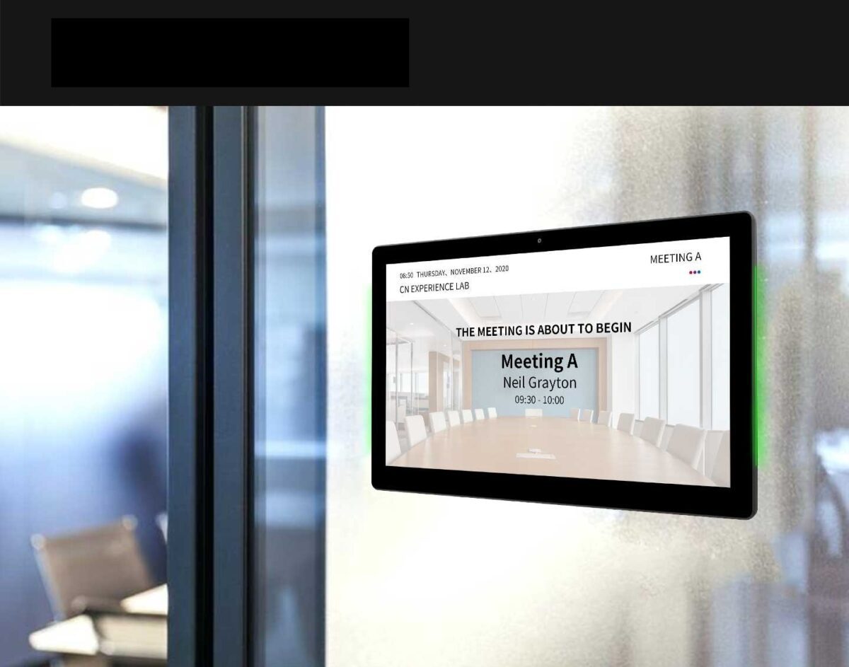 A GK-1052PL-MR 10" Android POE Wall Mount Meeting Room Display w LED status bar (Optional Meeting Room App) is displayed on a wall in a conference room.