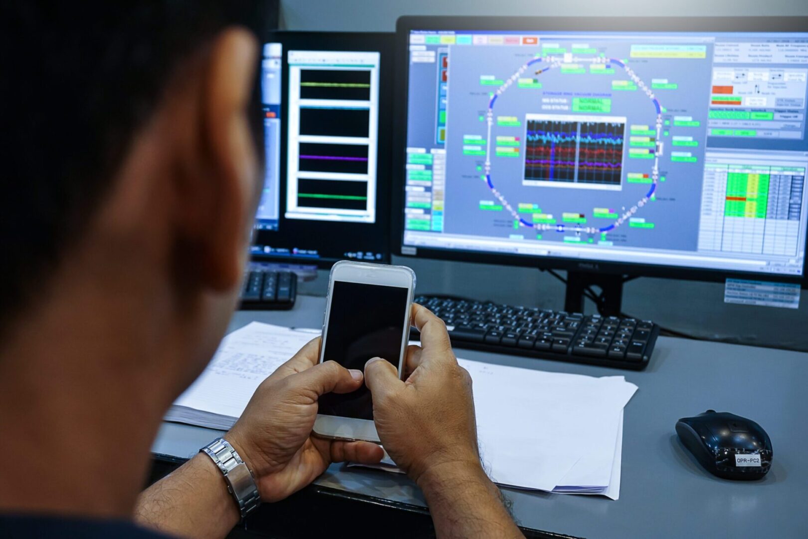 A person using a phone while in front of a laptop